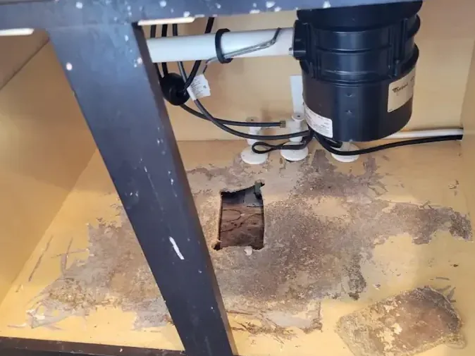 Sink cabinet floor with an access hole cut below the plumbing to dry the space underneath