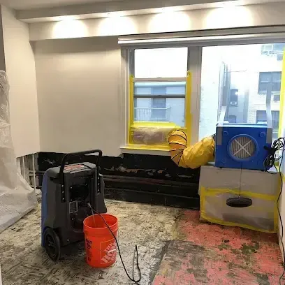 Restoration technician checking a wet wall with a moisture meter inside a home