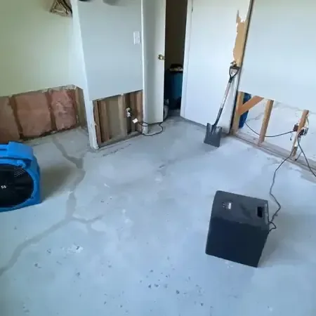 Living room floor covered in standing water with a technician setting up an air mover