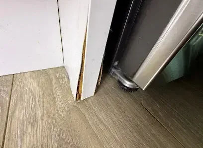 Kitchen appliance pulled out of its cabinet space above a wet plank floor