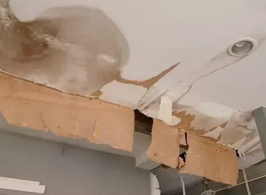 Stained ceiling drywall sagging and split open beneath a leak