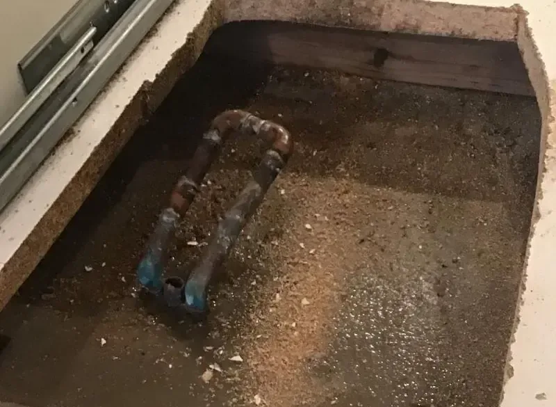 Concrete floor cut open to reach a leaking copper pipe beneath a house